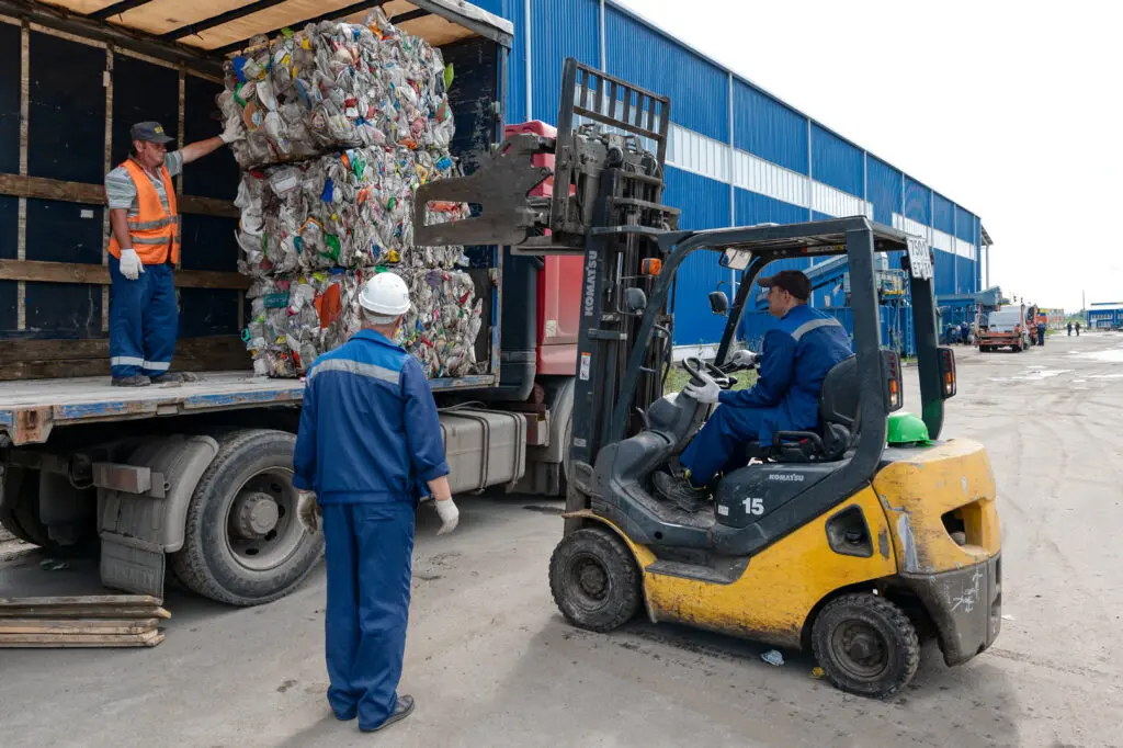 Plastic recycling facility bale with workers on truck